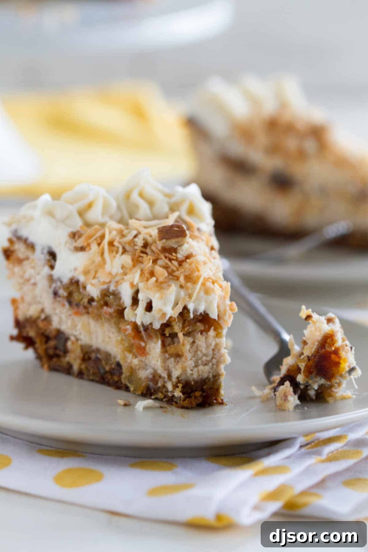 Savor every bite of this luxurious Carrot Cake Cheesecake, where layers of spiced cake and creamy cheesecake create an irresistible harmony of flavors and textures. A close-up shot of a slice of Carrot Cake Cheesecake, with a forkful already taken, showcasing the moist carrot cake layers and creamy cinnamon cheesecake filling, topped with toasted coconut and pecans.