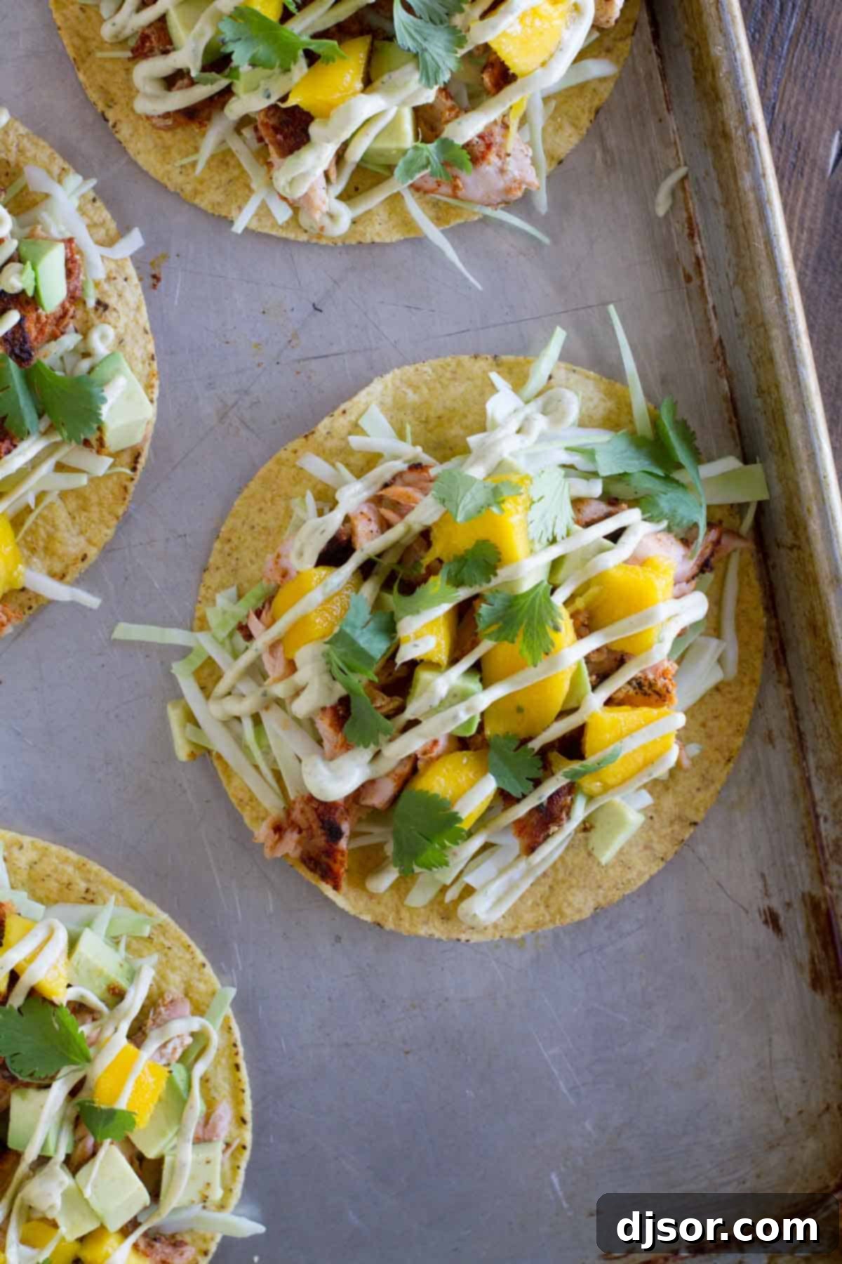 Several Blackened Salmon Tostadas arranged on a rustic baking sheet, showcasing their vibrant colors and crispy bases.