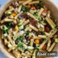 Wooden bowl full of Mediterranean Pasta Salad with pasta, olives, feta, and more.