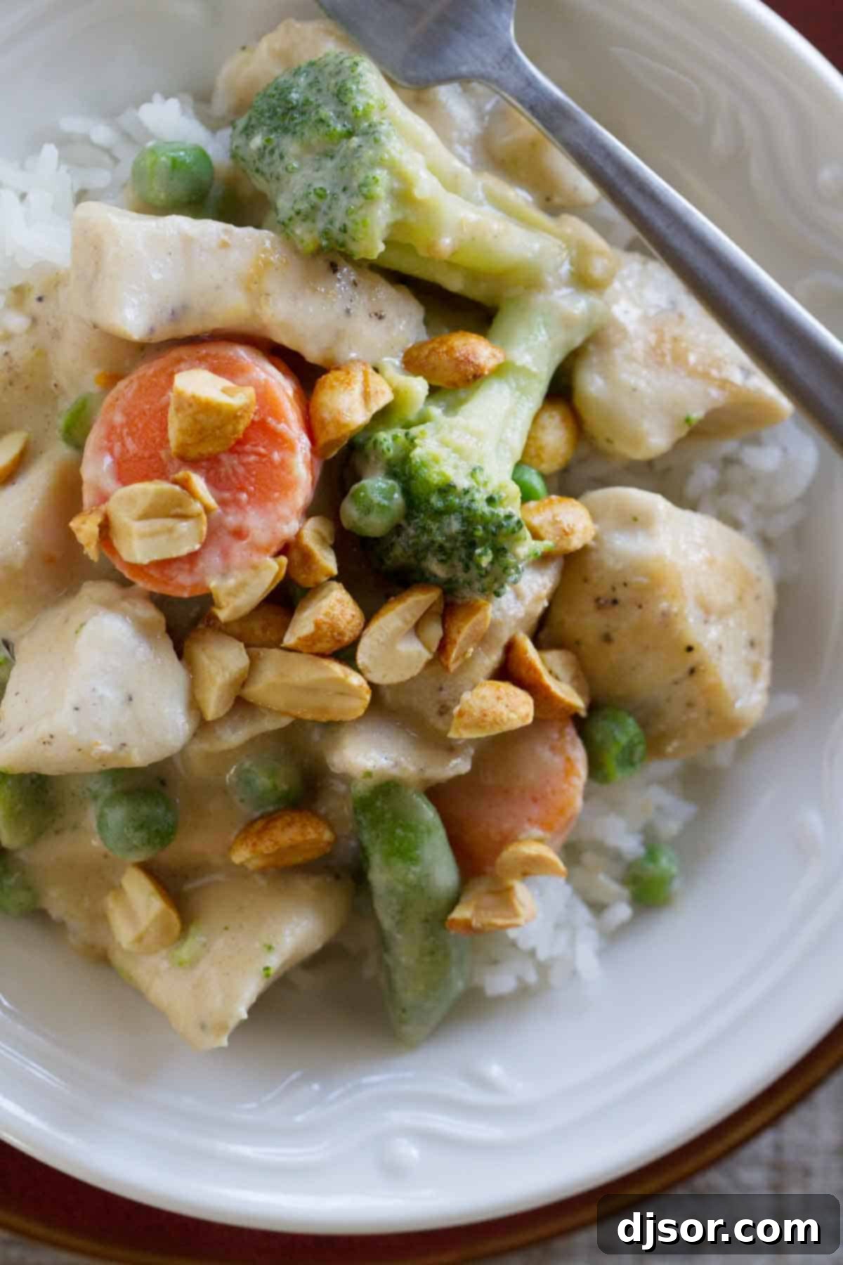 Peanut sauce doesn’t have to be reserved for satay - this Peanut Chicken Stir Fry has a coconut milk and peanut sauce, lean chicken breasts, and lots of veggies. It is the perfect weeknight dinner. peanut chicken with vegetable and rice topped with peanuts