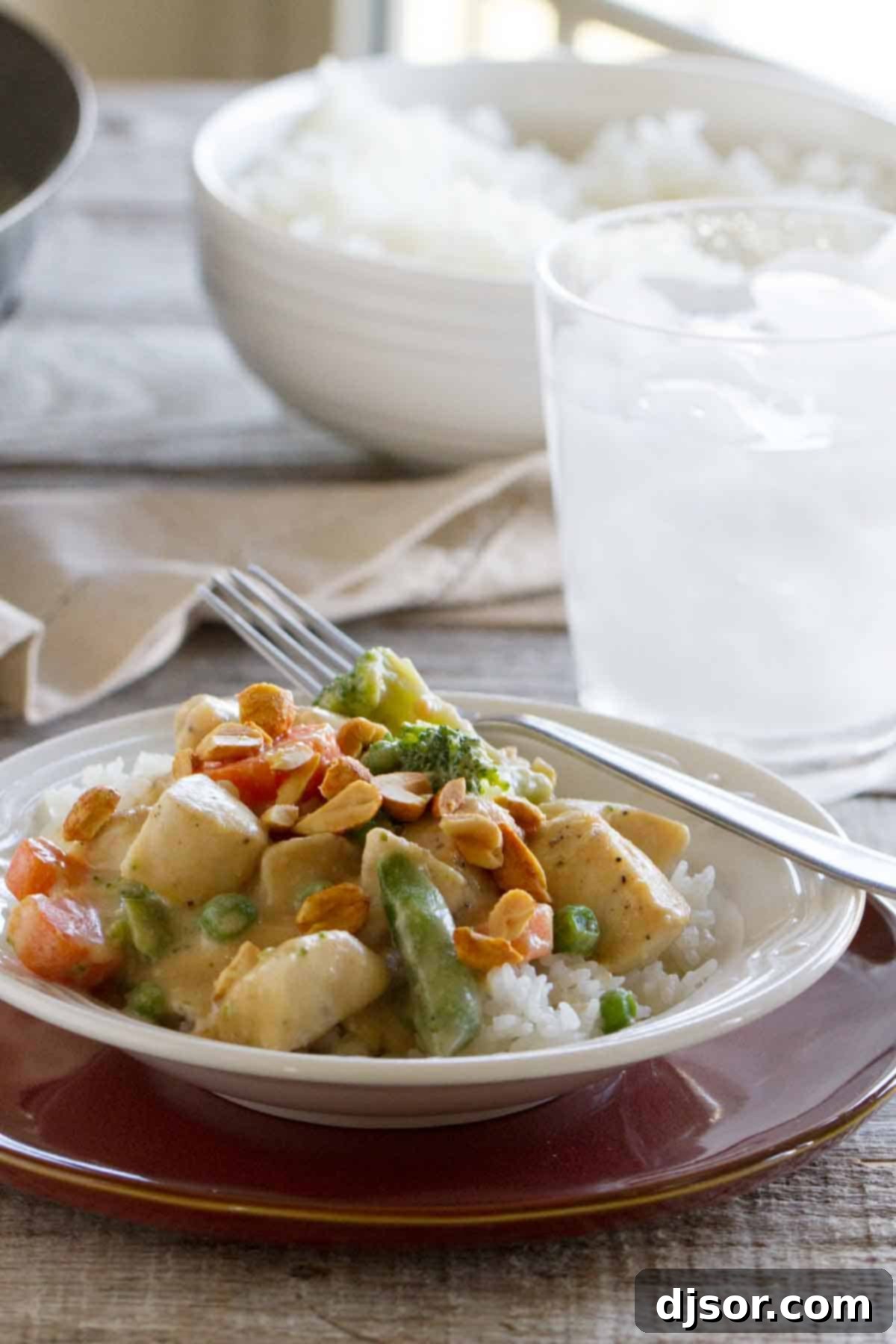 Peanut sauce doesn’t have to be reserved for satay - this Peanut Chicken Stir Fry has a coconut milk and peanut sauce, lean chicken breasts, and lots of veggies. It is the perfect weeknight dinner. Peanut Chicken Stir fry with rice in a bowl