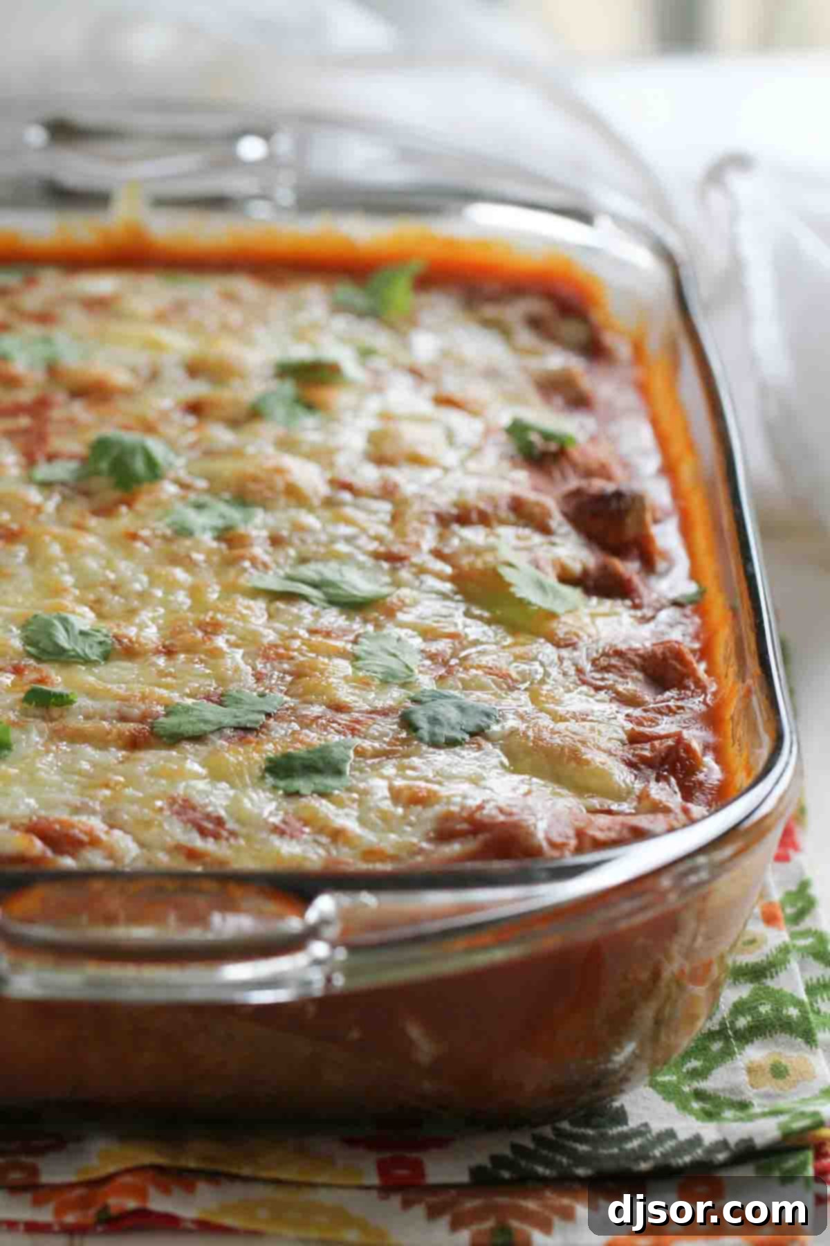 A rectangular baking dish filled with golden-brown spinach artichoke enchiladas, fresh from the oven, with melted cheese bubbling on top, ready to be served.