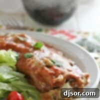 A single Spinach Artichoke Enchilada on a plate with a salad, showcasing the golden-brown melted cheese and vibrant green filling.