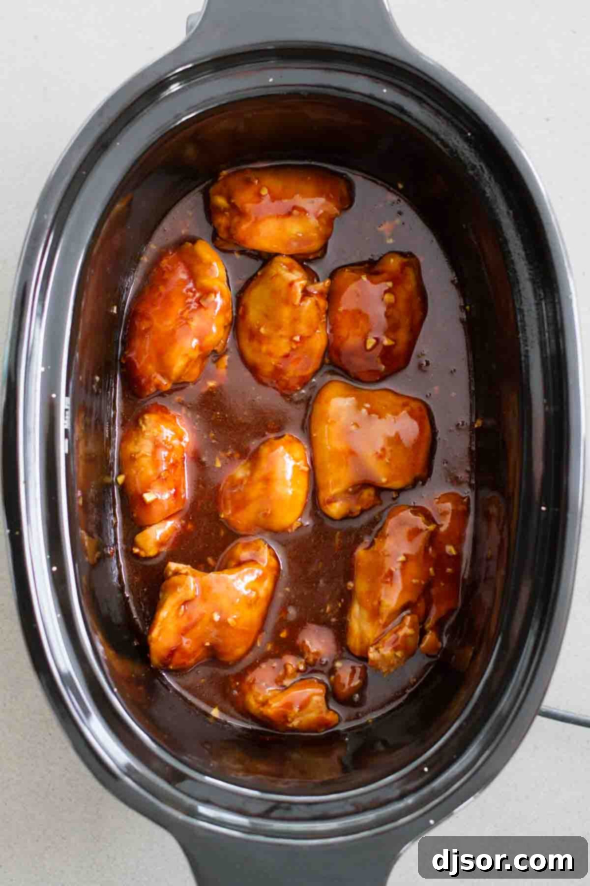 Honey garlic chicken thighs simmering in a crockpot, filling the kitchen with a delightful aroma.