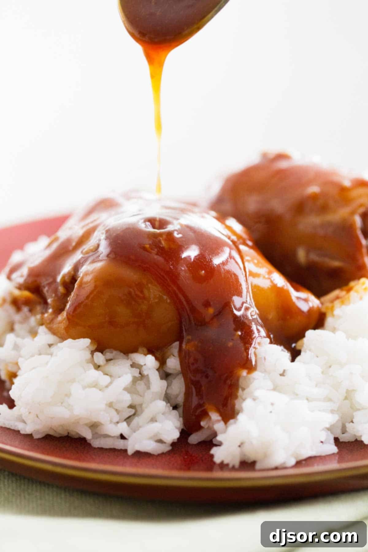 Close-up of thick honey garlic sauce being drizzled over cooked chicken.