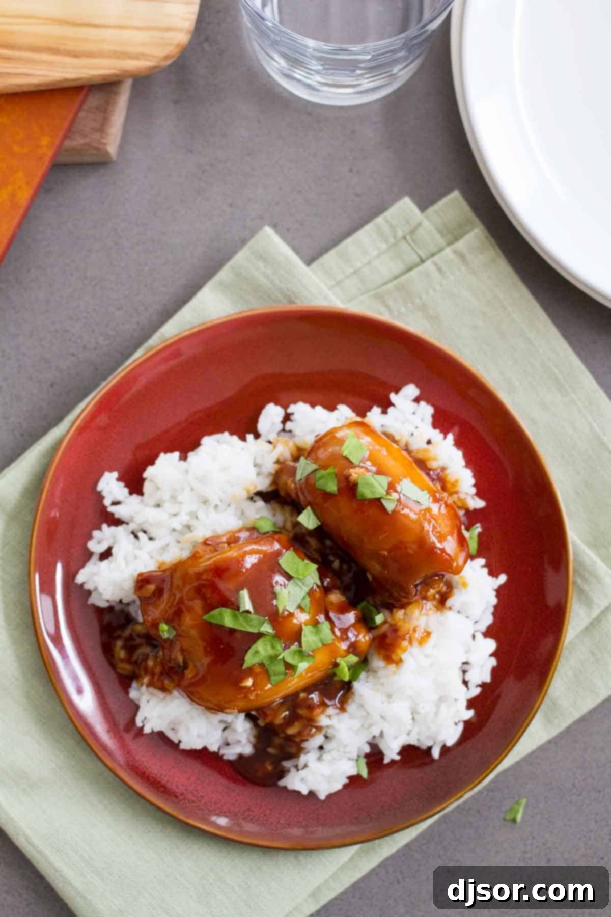 A serving of Slow Cooker Honey Garlic Chicken over rice, garnished with fresh basil leaves.