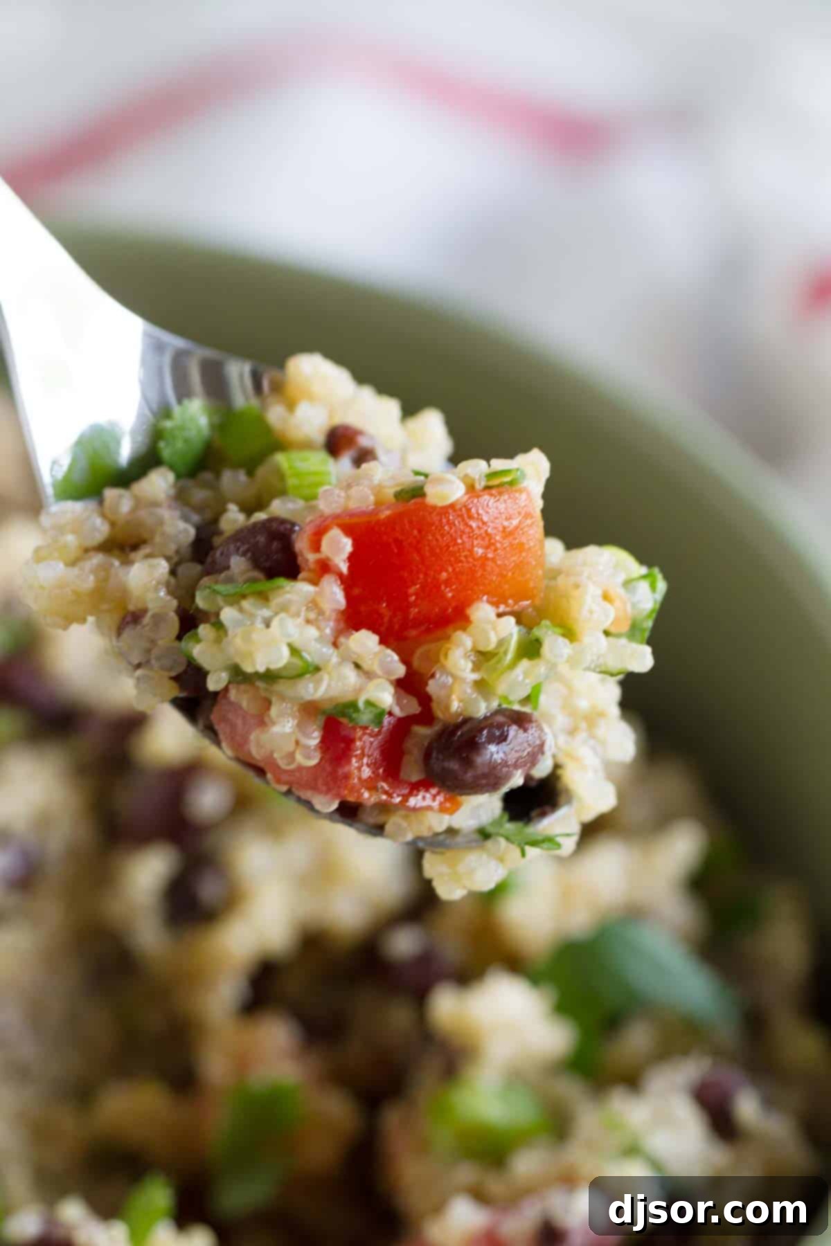 A spoonful of fresh Tomato and Black Bean Quinoa Salad, showcasing its vibrant ingredients.