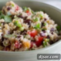 Tomato and Black Bean Quinoa Salad, beautifully garnished with fresh green onions and cilantro on top.