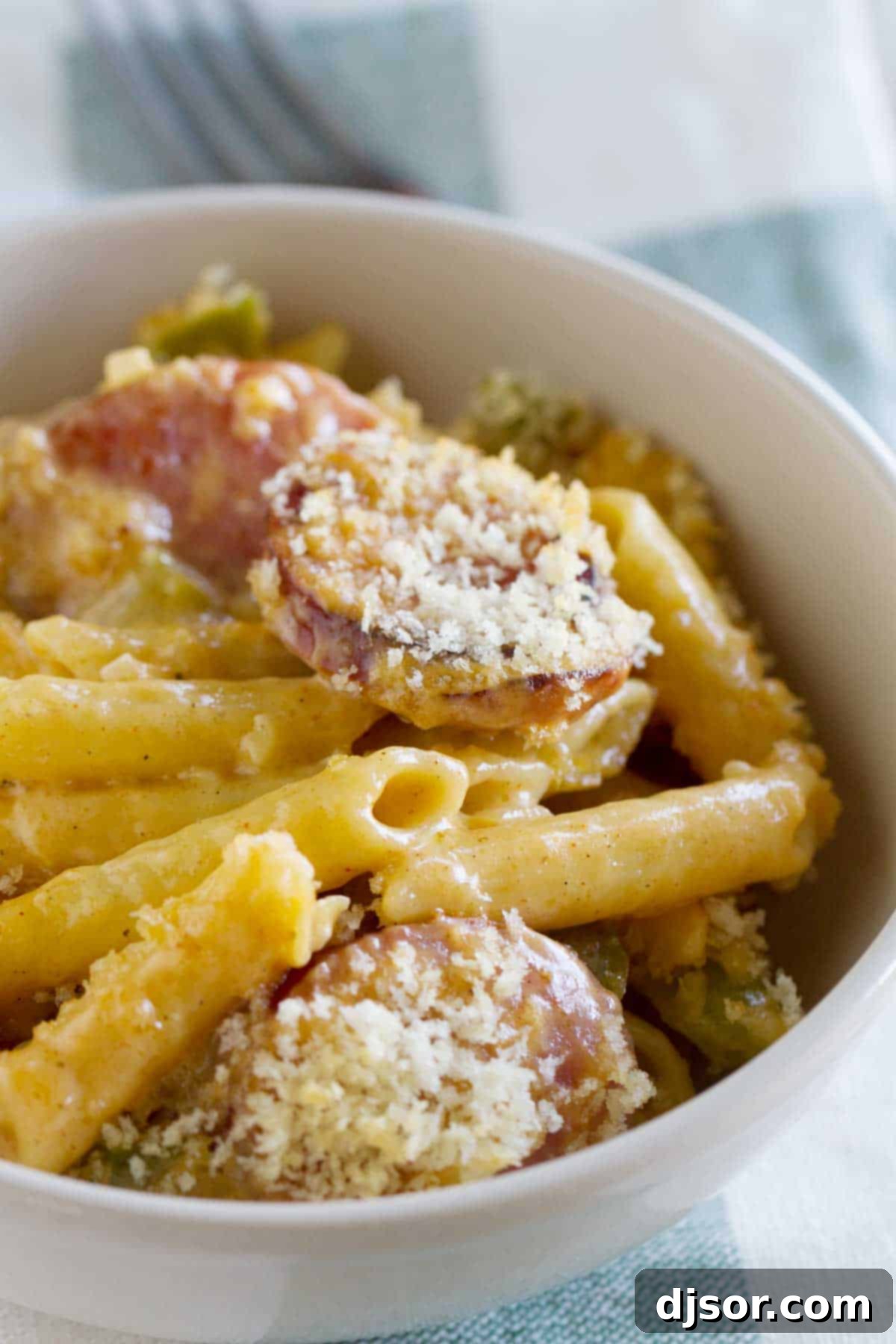 Bayou Cheesy Pasta Bake 3 Close-up shot of a bowl brimming with creamy Cheesy Baked Cajun Pasta, topped with golden-brown breadcrumbs and hints of sausage and bell pepper.