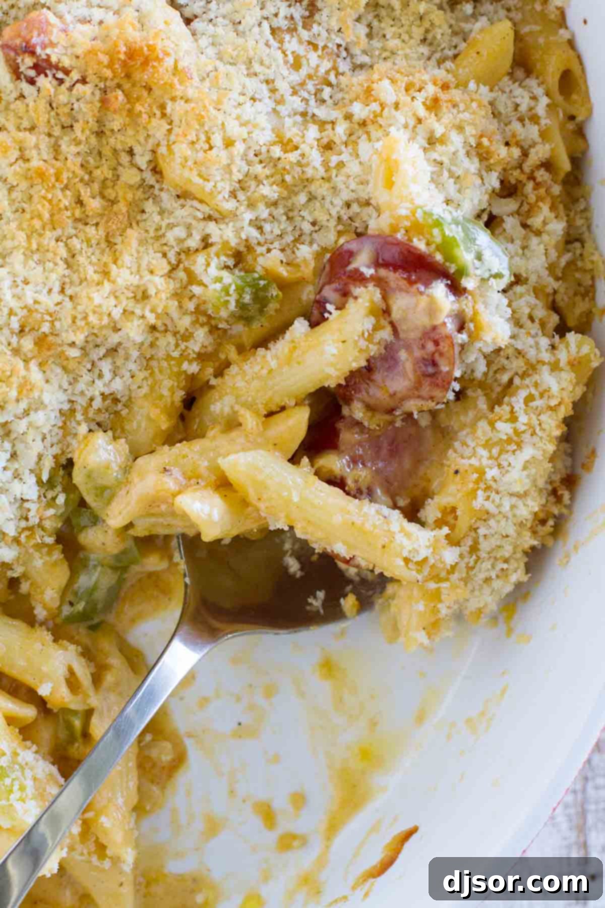 Bayou Cheesy Pasta Bake 4 A large rectangular casserole dish filled to the brim with Cheesy Baked Cajun Pasta, freshly baked with a golden breadcrumb topping, ready to be served.