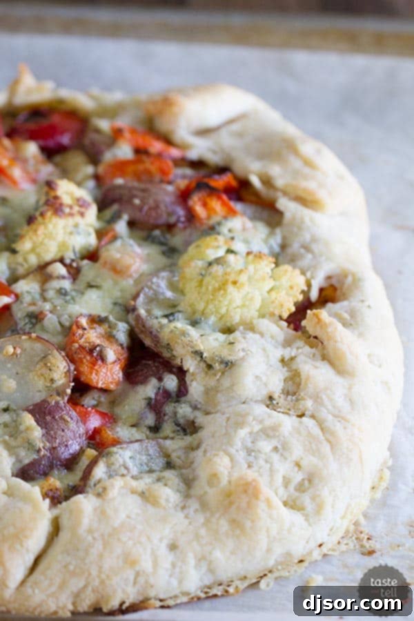 Rustic Roasted Vegetable Galette 2 A vibrant Crostata with a golden crust, generously filled with an assortment of oven-roasted vegetables like potatoes, carrots, cauliflower, and red bell pepper, with crumbled blue cheese visible on top.