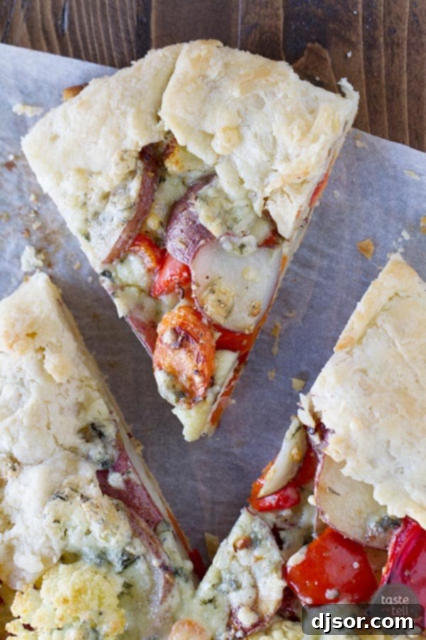 Rustic Roasted Vegetable Galette 3 A close-up view of a slice of Crostata with Oven Roasted Vegetables on a white plate, showcasing the perfectly roasted vegetables, melted blue cheese, and a flaky golden crust.