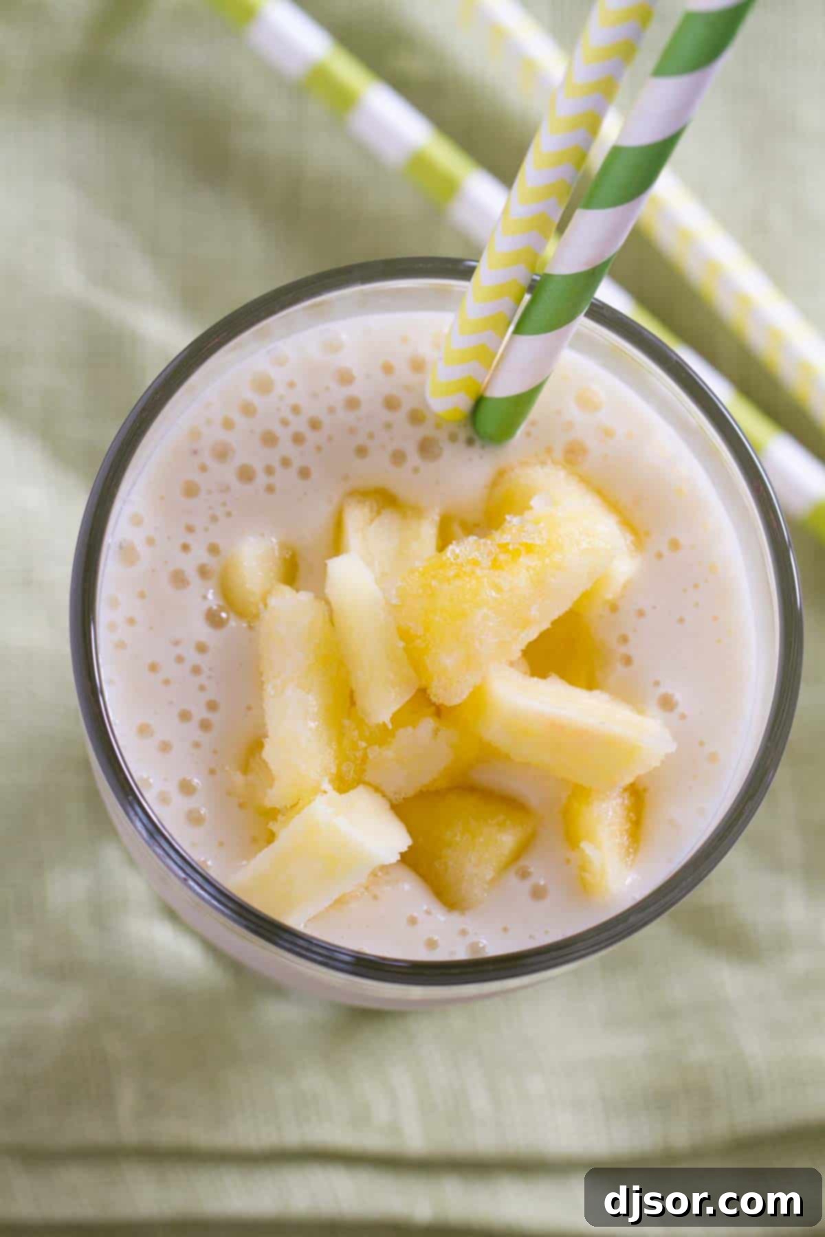 Close-up top-down view of a Pineapple Banana Smoothie, garnished with a fresh pineapple wedge, highlighting its creamy texture and inviting tropical appeal. A perfect refreshing beverage.