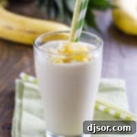 Pineapple Banana Smoothie in a glass with two straws.