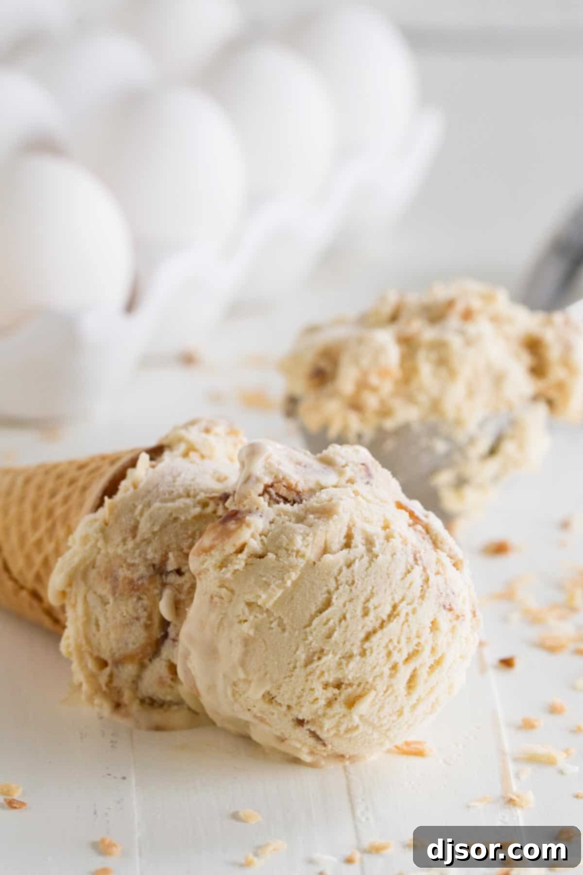 A scoop of rich salted caramel ice cream with visible fudge swirls and toasted coconut flakes, served on its side in a sugar cone, showcasing its creamy texture.