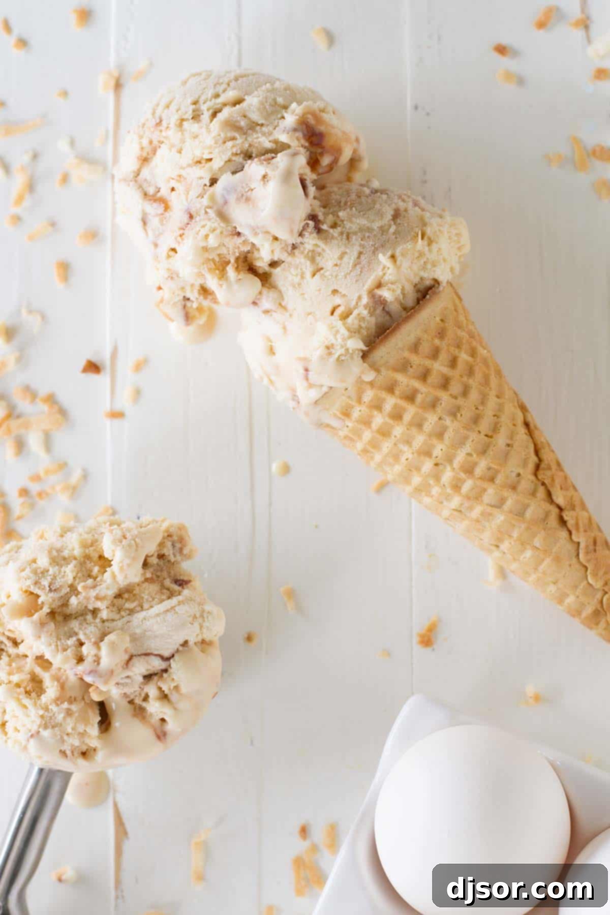 Two generous scoops of salted caramel ice cream, beautifully swirled with rich fudge and sprinkled with toasted coconut, resting in a crisp sugar cone.