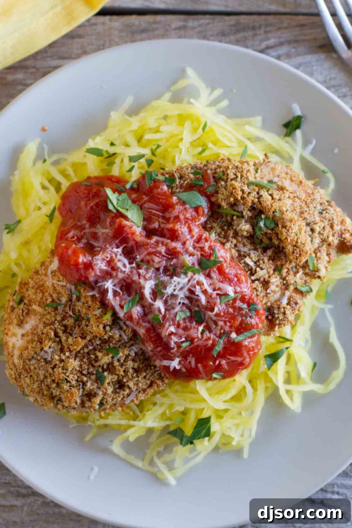 Baked Chicken Parmesan served over a bed of spaghetti squash, garnished with fresh basil.