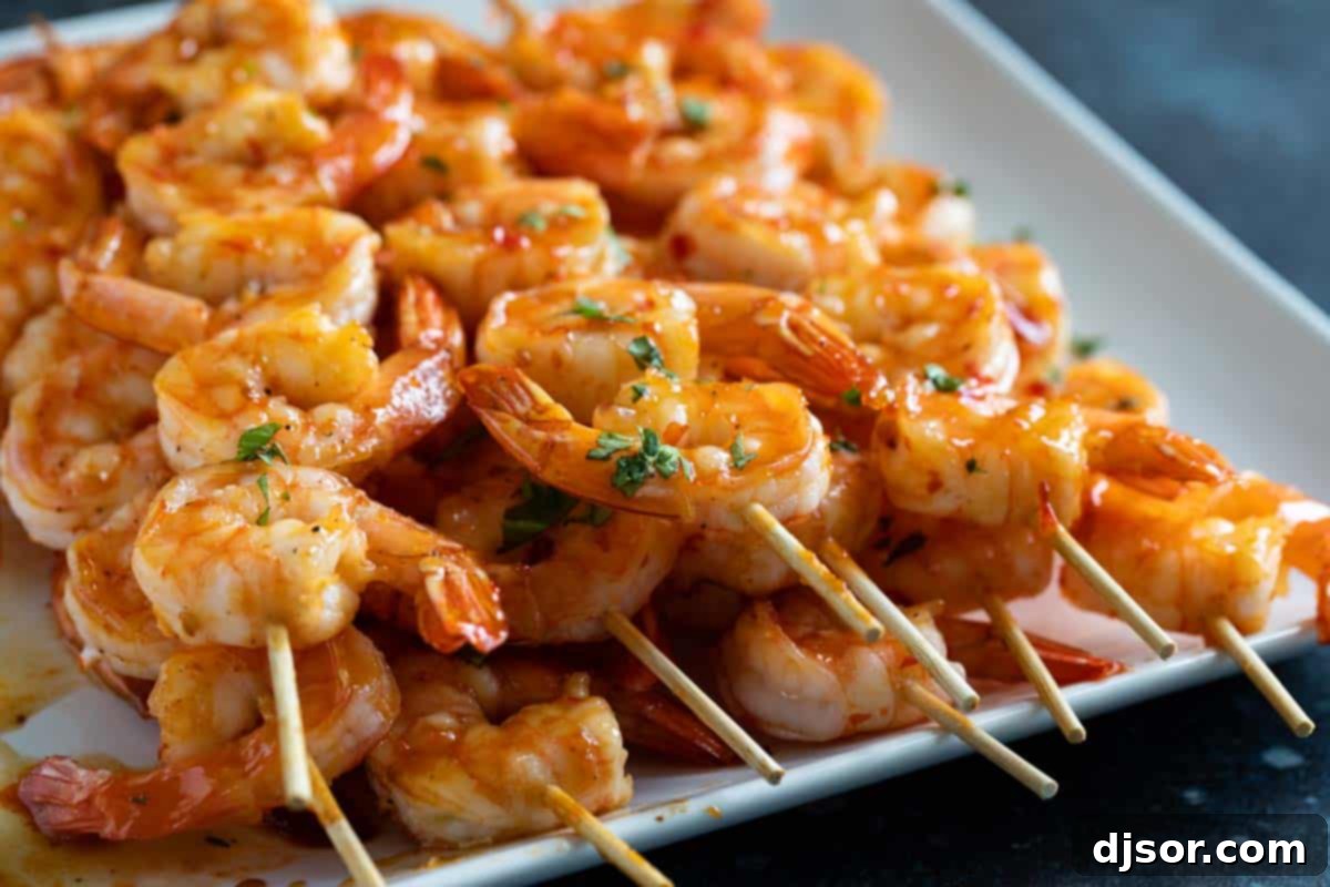 Chili Honey Garlic Shrimp Kabobs stacked on a serving plate.
