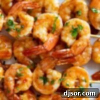 Chili Honey Garlic Shrimp Kabobs stacked on a plate.