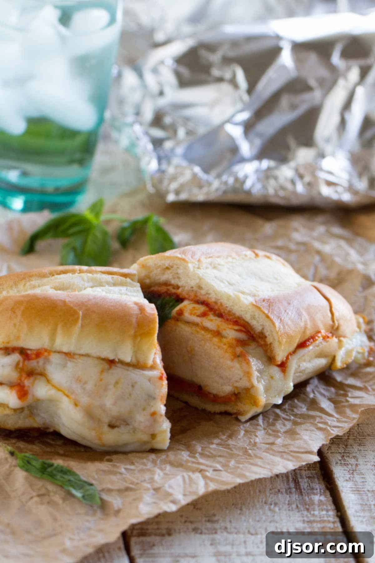 Baked Chicken Parmesan Sandwich cut in half to show its interior layers of breaded chicken, marinara, and melted cheese.