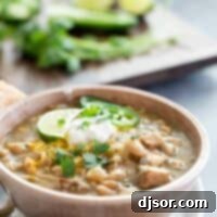 bowl of white turkey chili with beans topped with sour cream and jalapeno