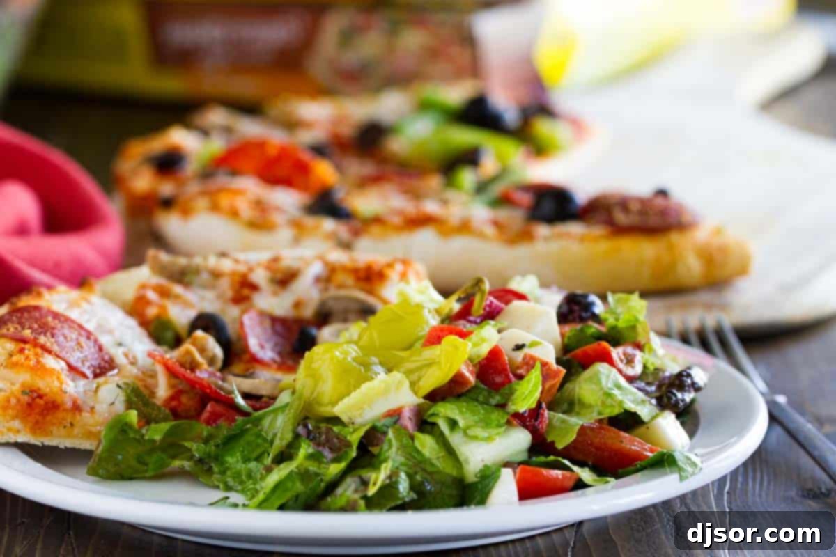 Elevate Your Pizza Night with Antipasto Salad A serving of Antipasto Salad next to a slice of pizza, showcasing the perfect pairing.
