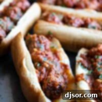 Irresistible Meatball Sub 2 several meatball subs on a tray topped with marinara and parsley