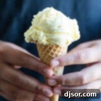 hands holding a scoop of ice cream in a sugar cone