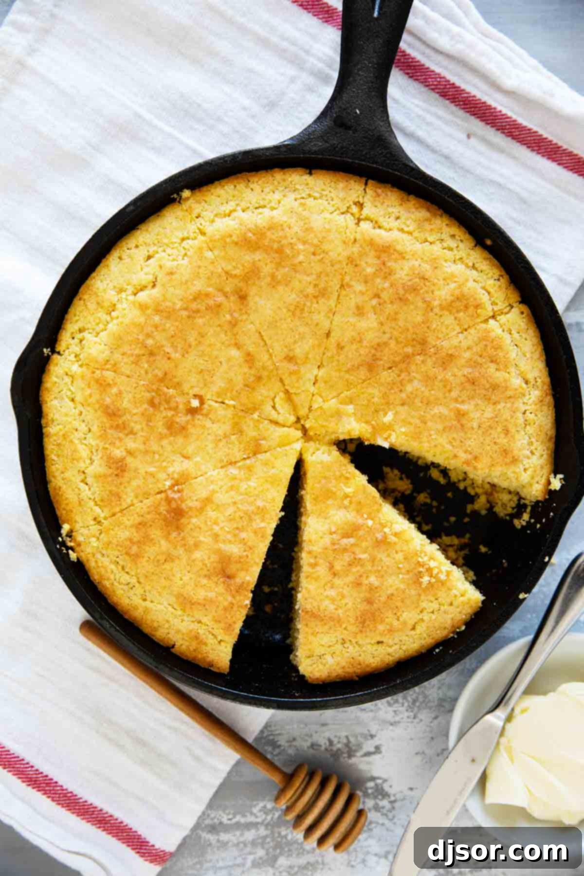 A freshly baked cornbread, perfectly golden and cut into neat, inviting slices, resting in a seasoned cast iron pan, ready to be served.