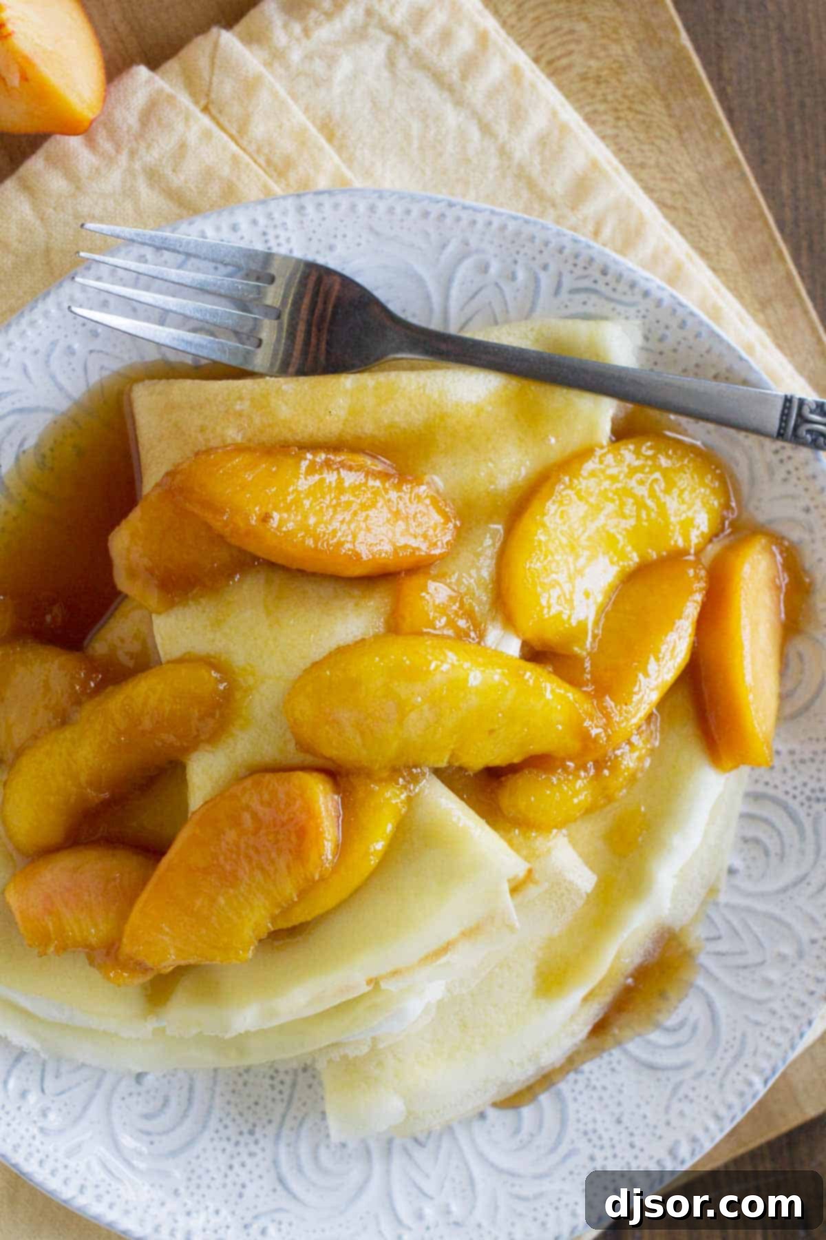 Sweet Crepes with Peaches - A perfect blend for breakfast or dessert. Sweet Crepes topped with Peaches on a plate