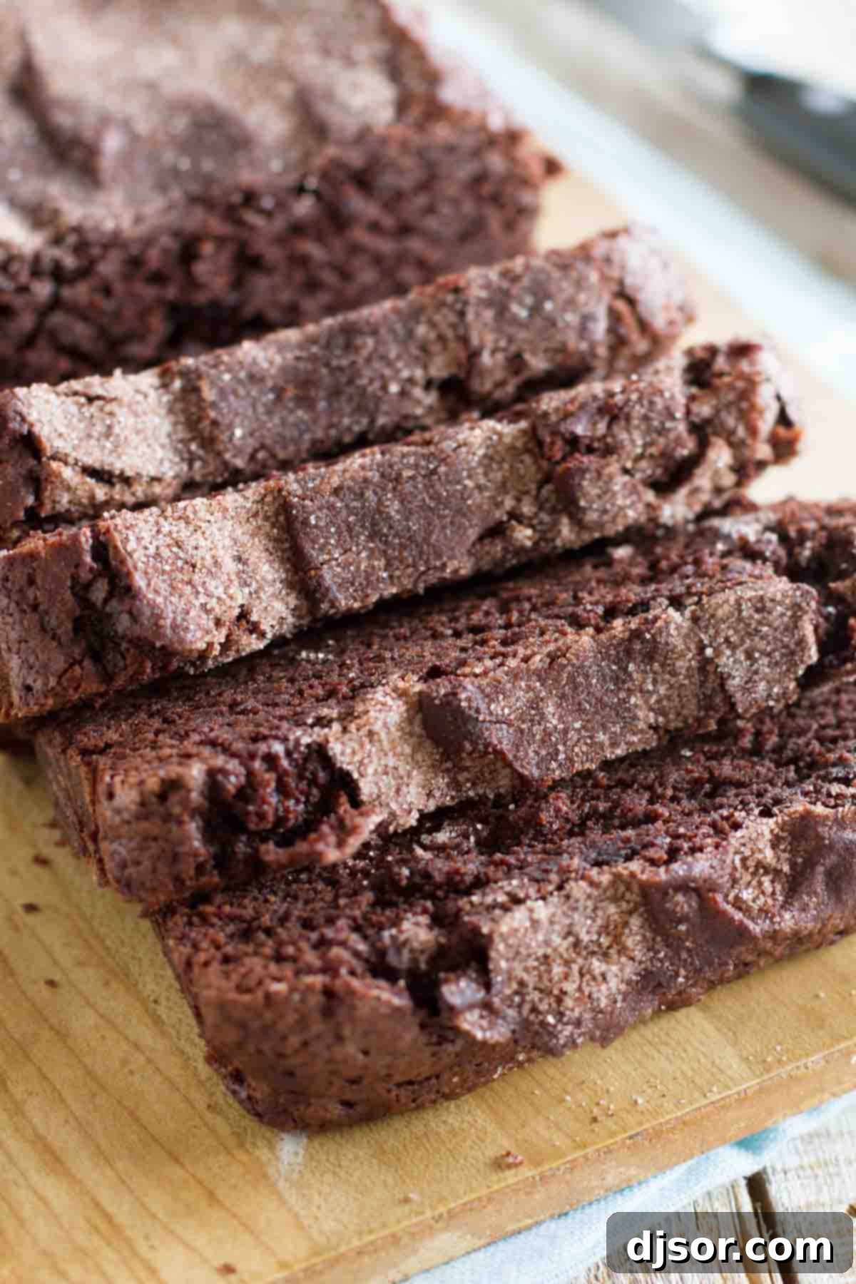 Chocolate Cinnamon Swirl Bread 2 A perfectly baked loaf of sliced chocolate cinnamon bread resting on a rustic wooden cutting board, ready to be served.