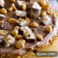 Close up view of a Snickers Cheesecake slice, showcasing the layers and toppings.