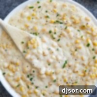 Velvety Sweet Corn 8 Creamed Corn topped with pepper and chives in a white serving bowl.