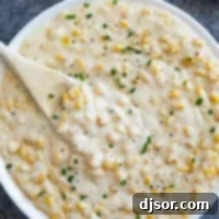 Velvet Corn Bliss 7 Creamed Corn topped with pepper and chives in a white serving bowl.