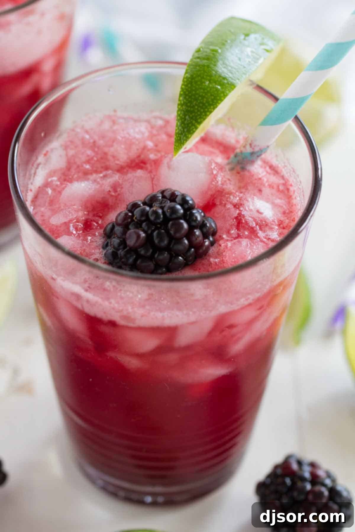 Blackberry Lime Soda: Simple and Delicious Two glasses of blackberry lime soda with ice and fresh fruit, set against a bright, airy background
