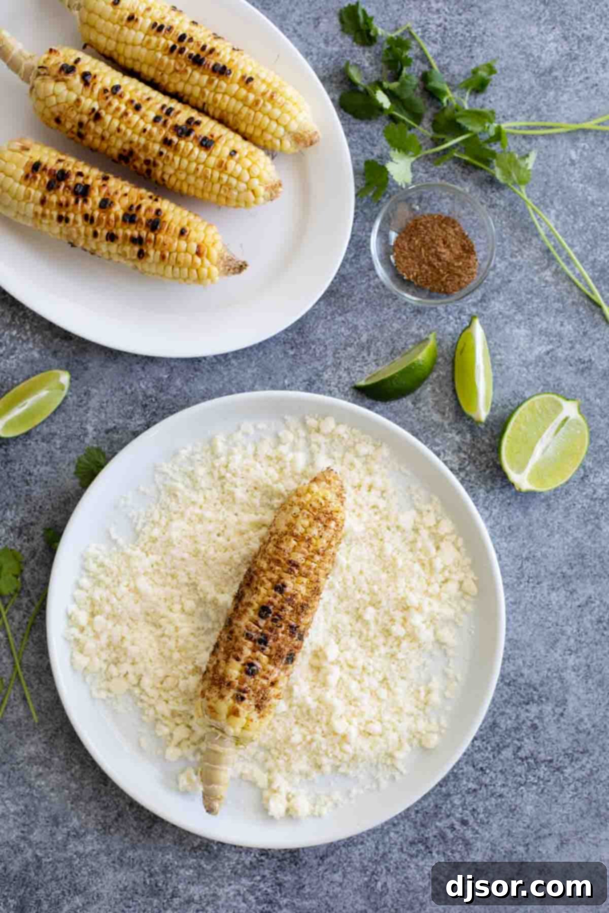 Grilled corn - south of the border style! This Grilled Mexican Corn on the Cob takes grilled corn to the next level with spices, crumbled Cotija cheese, cilantro and fresh squeezed lime. Rolling freshly grilled corn on the cob in crumbled Cotija cheese, ready for serving.