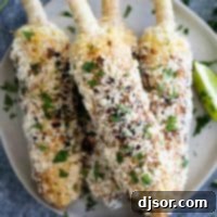 Mexican Street Corn 2 Four delicious Elotes (Grilled Mexican Corn on the Cob) stacked neatly on a white plate, garnished with fresh cilantro and lime.