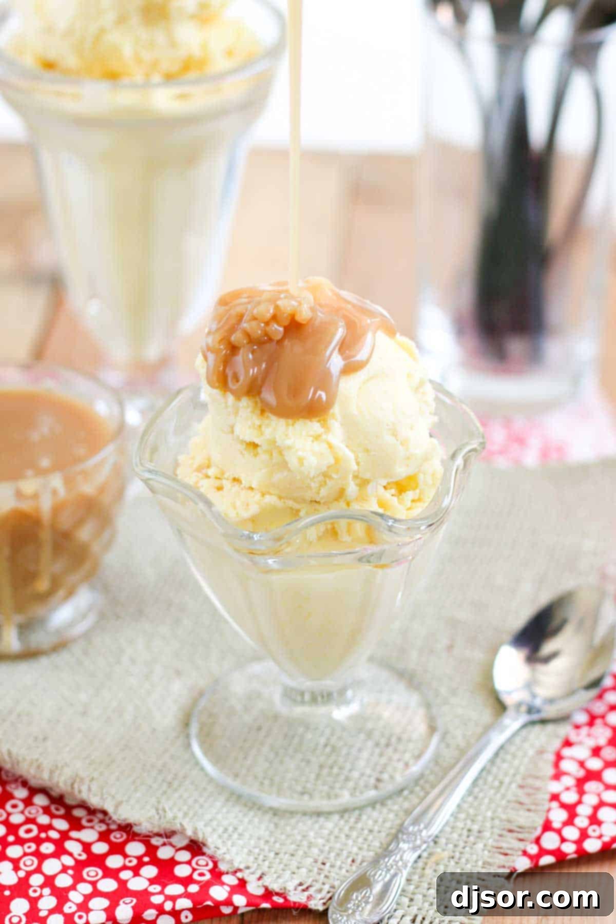 Pouring homemade salted caramel sauce over the top of sweet corn ice cream in a glass cup.