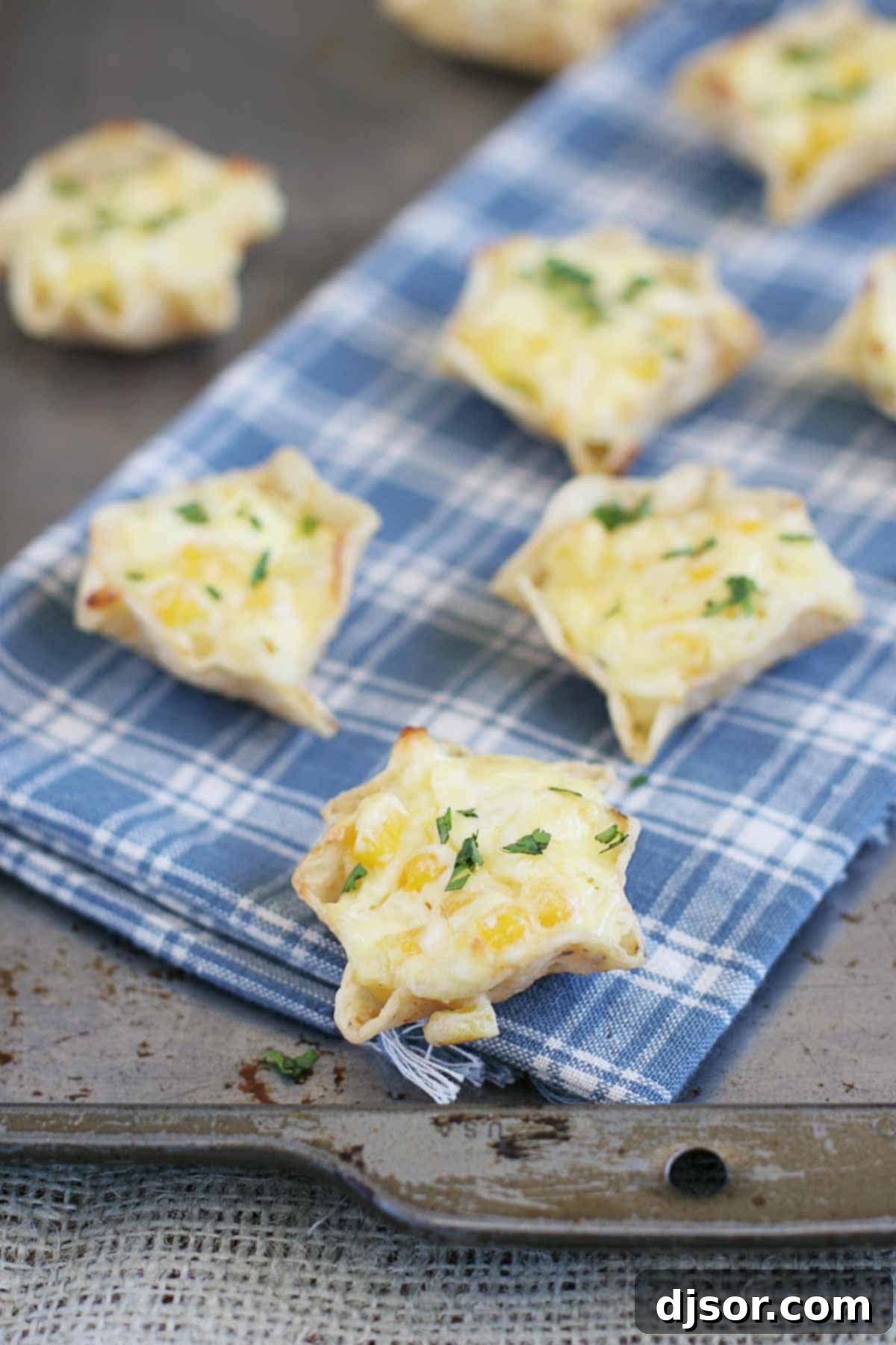 Cheesy Corn Bites topped with fresh cilantro, beautifully arranged on a white towel over a baking sheet, ready to be served.