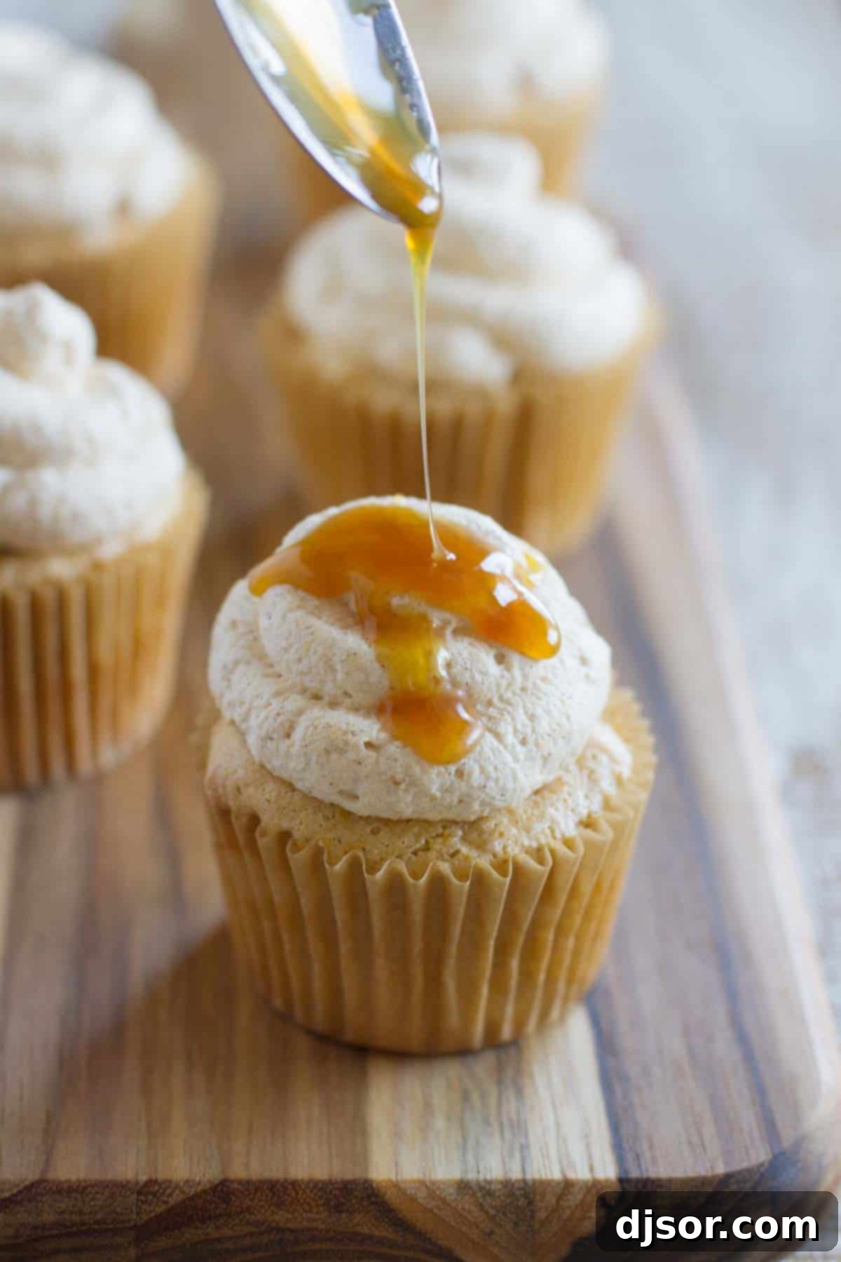 Pumpkin Cloud Cupcakes 3 Close-up of a Pumpkin Angel Food Cupcake being drizzled with rich, golden caramel sauce, highlighting its soft texture.