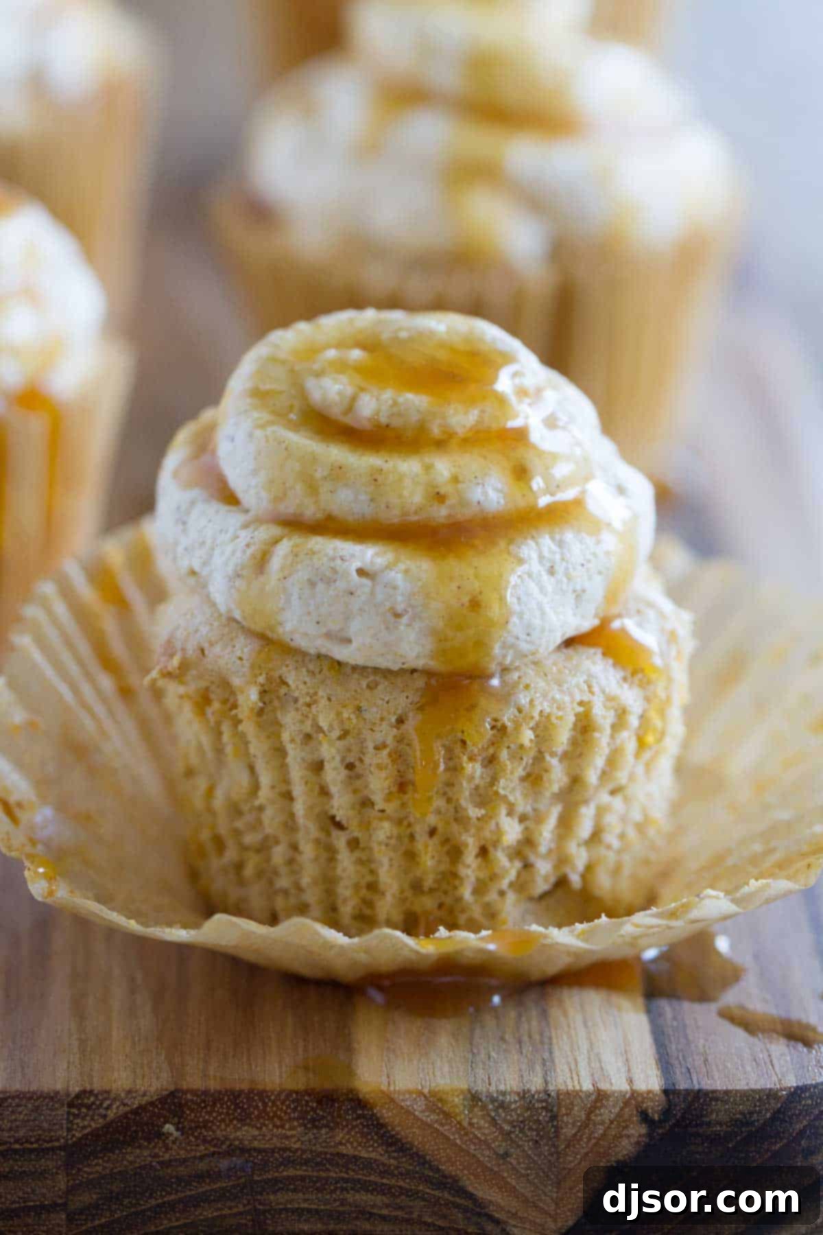 Pumpkin Cloud Cupcakes 4 A single Pumpkin Angel Food Cupcake, with its wrapper removed, revealing a soft, golden interior, drizzled with caramel.