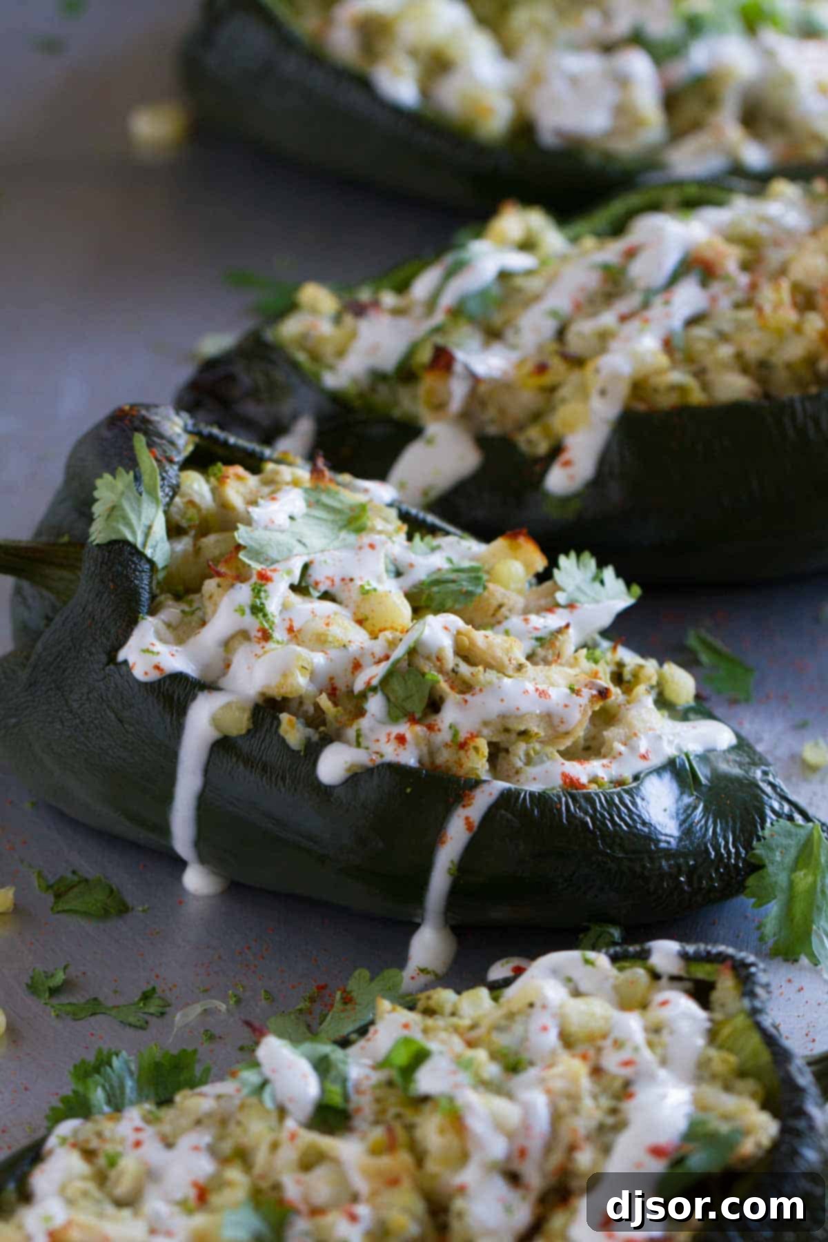 Flavor explosion! These Stuffed Poblano Peppers with Chicken and Corn are packed with flavor – chicken, corn, cheese and salsa all inside a mild poblano pepper. Don’t skip the lime cream! A line of golden-brown stuffed poblano peppers on a baking sheet, overflowing with a delicious chicken and corn filling, and beautifully topped with a drizzle of refreshing lime cream.