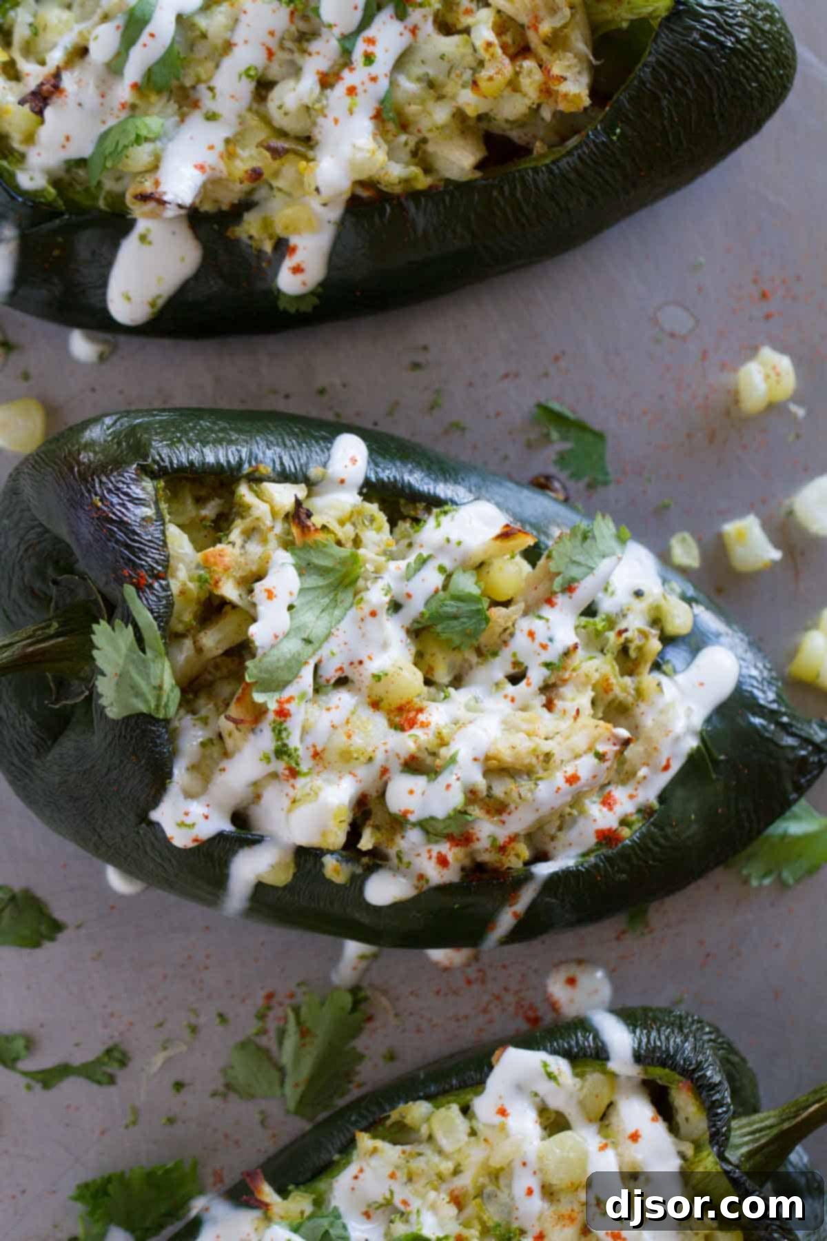 Hearty Chicken and Corn Stuffed Poblano Peppers 3 A trio of perfectly roasted poblano peppers, each generously stuffed with a savory chicken and corn mixture and finished with a beautiful drizzle of zesty lime cream, ready to be served.