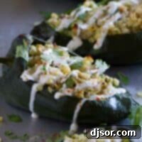 Hearty Chicken and Corn Stuffed Poblano Peppers 4 A line of stuffed poblano peppers on a baking sheet. the peppers are filled with chicken and cheese and topped with lime cream.