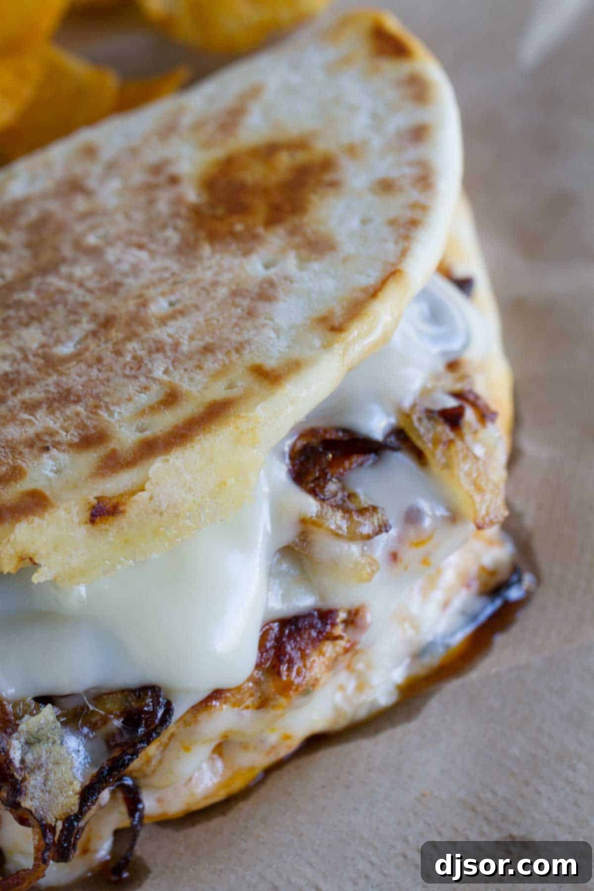 Sizzling Chorizo-Chicken Melt 3 Close-up of a halved Chicken and Chorizo Patty Melt, revealing layers of patty, melted Swiss cheese, and golden caramelized onions.