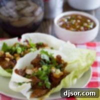 Smoky BBQ Pork Lettuce Cups 6 Two BBQ Pork Lettuce Wraps on a plate on top of a checkered cloth.