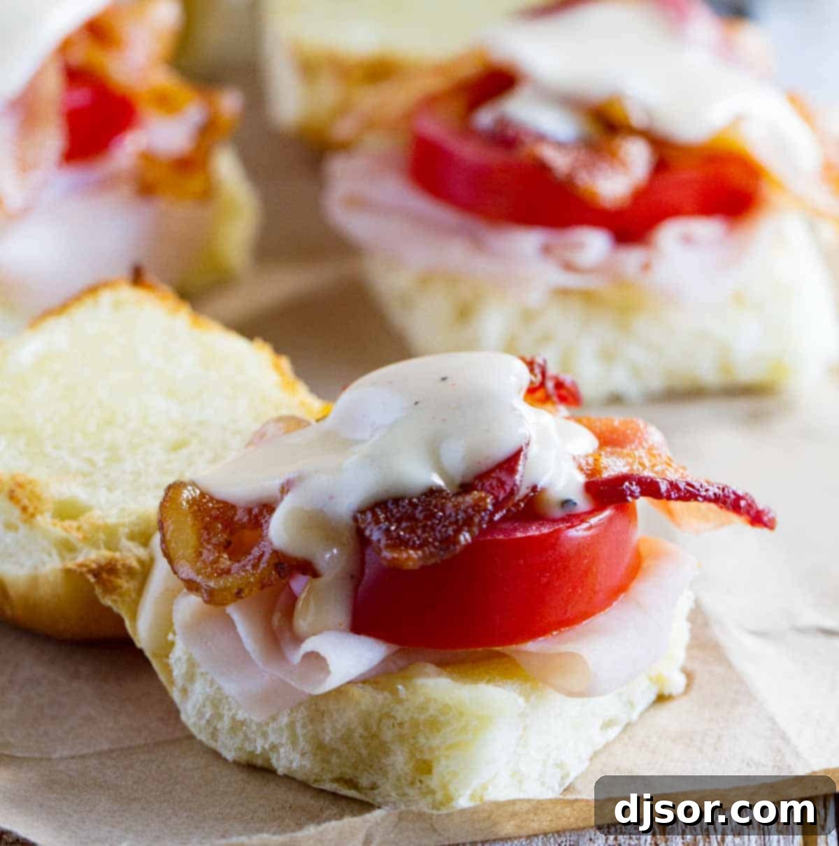 Close-up of the delicious insides of easy Kentucky Hot Brown Sandwiches, revealing layers of turkey, bacon, and melted cheese sauce.