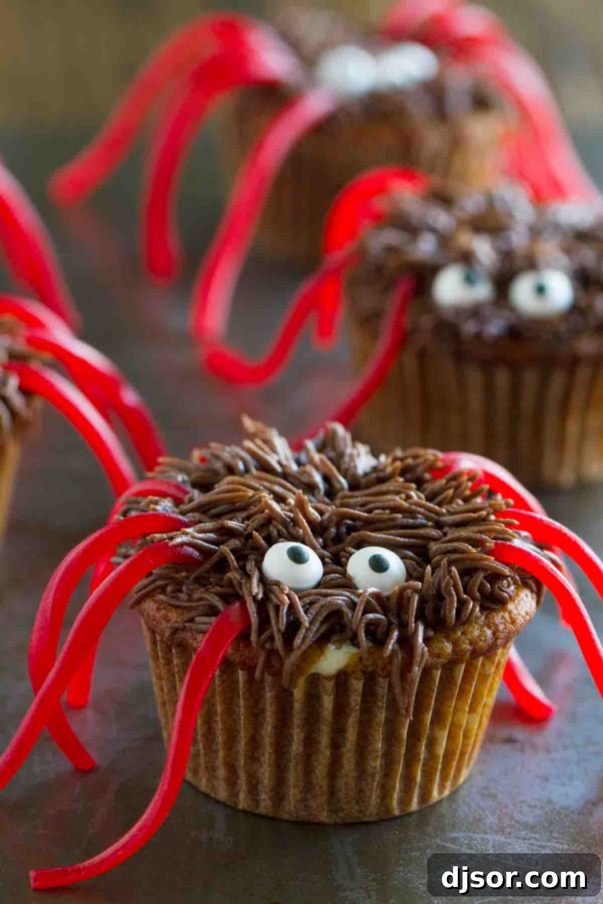 Pumpkin Cheesecake Spider Cupcakes arranged on a surface, ready to be enjoyed as a festive Halloween dessert.