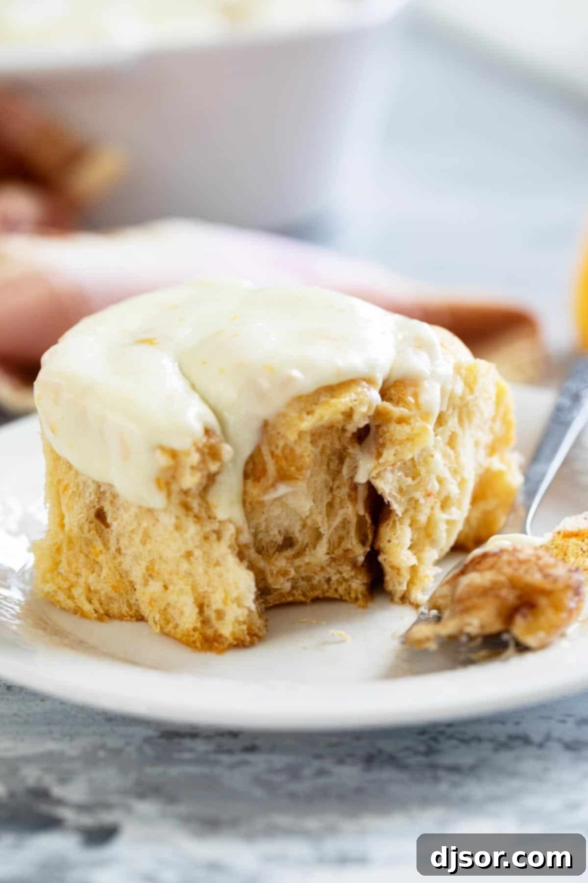 Sweet Potato Cinnamon Roll with a piece taken from it on a plate.