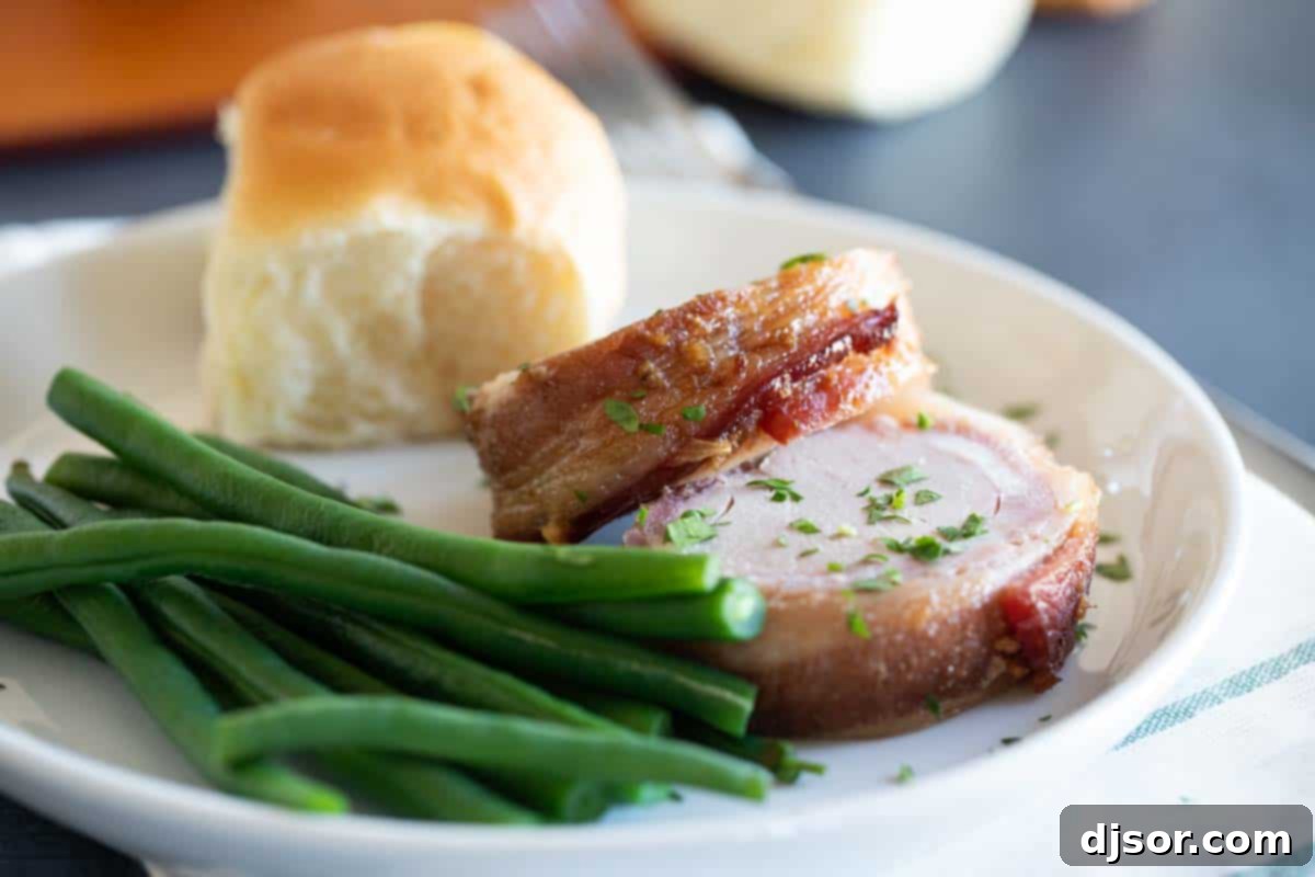 Plate with slices of Bacon Wrapped Pork Tenderloin and green beans, ready to serve